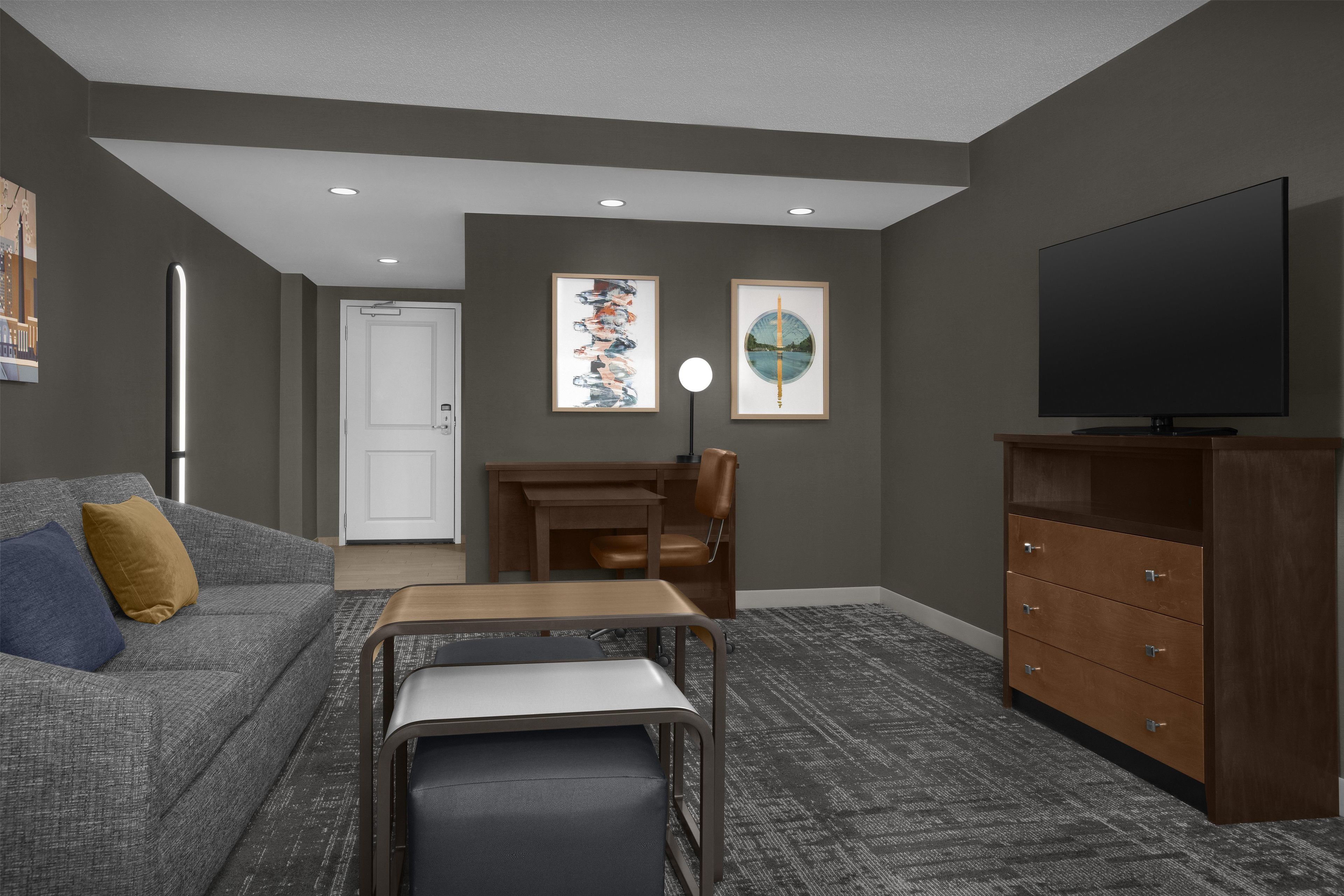 A living room with a sofa, a coffee table, a TV, a cabinet, and artwork on the wall.