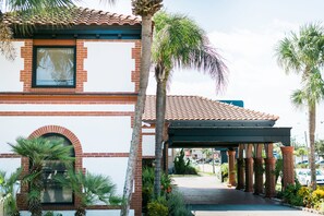 A building with a red brick facade, a tiled roof, and a covered entrance area with columns. - The Flagler Inn (St. Augustine)