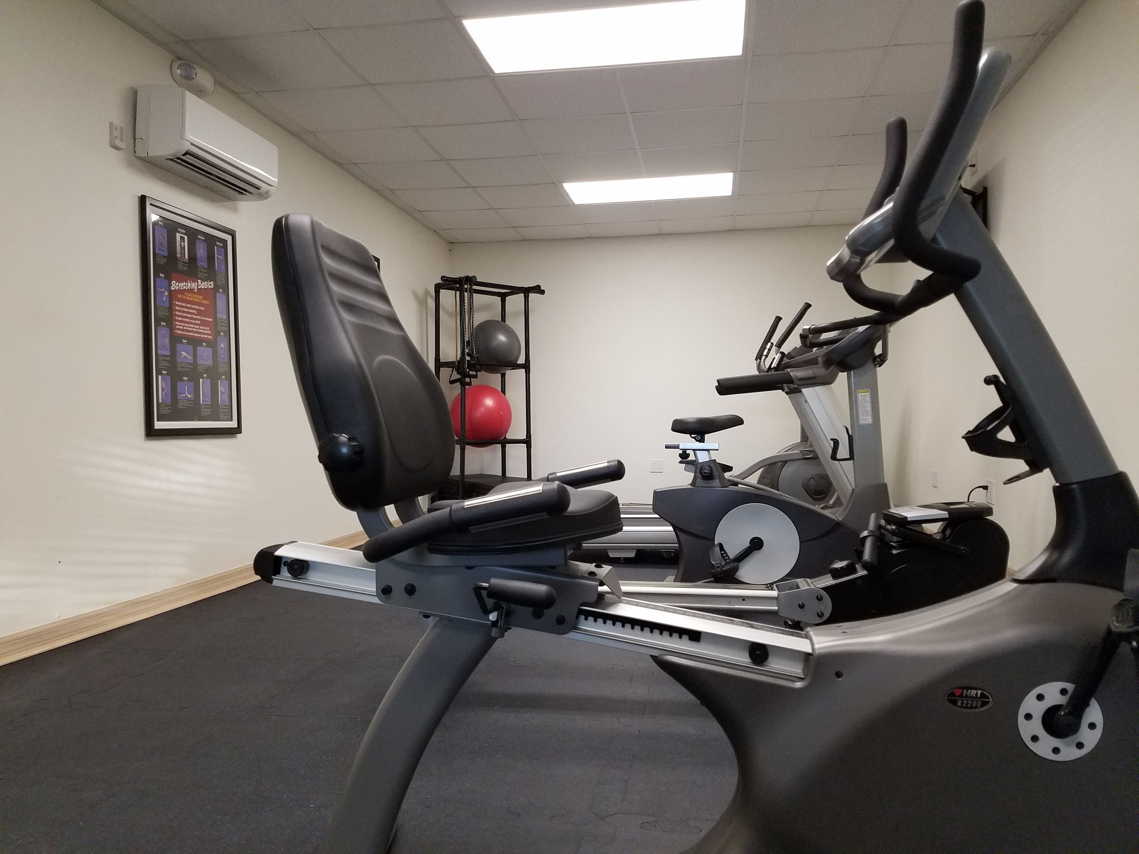 A stationary bike with a weight stack and a red medicine ball on a rack.