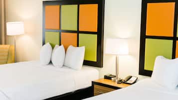 A hotel room with two beds, a nightstand with a lamp and phone, and a wall with a colorful panel design.