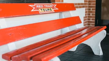 A red and white bench with a sign that reads "RED TRAIN TOURS".