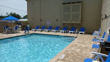 Una piscina al aire libre, sombrillas, sillones reclinables de piscina