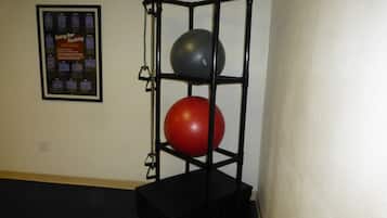 A black exercise ball rack with two exercise balls, one red and one black, against a wall.