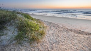 A beach with sand and grass, leading to the ocean. - The Flagler Inn (St. Augustine)