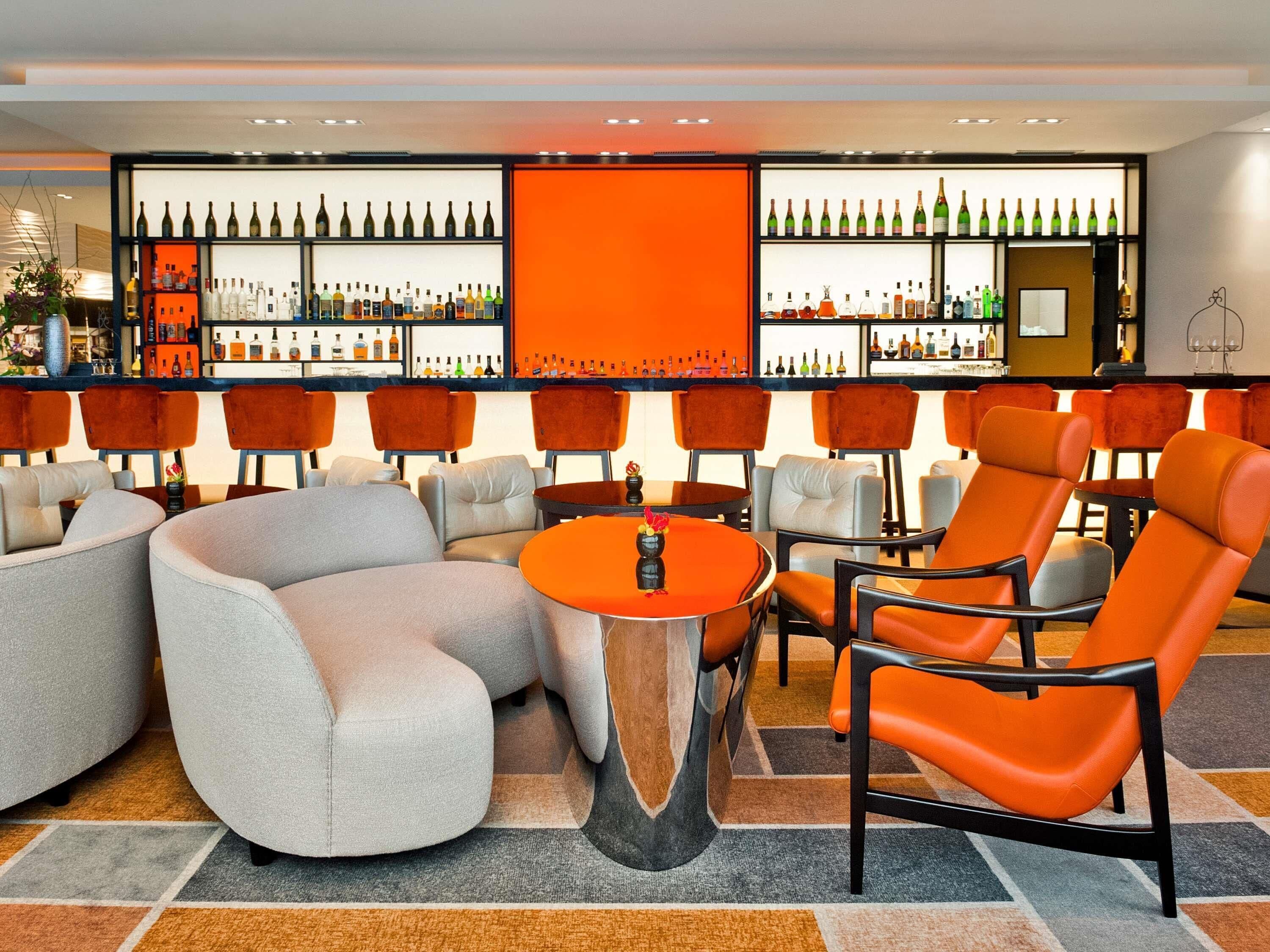 A bar area with seating, a bar counter with bottles, and a large orange partition.