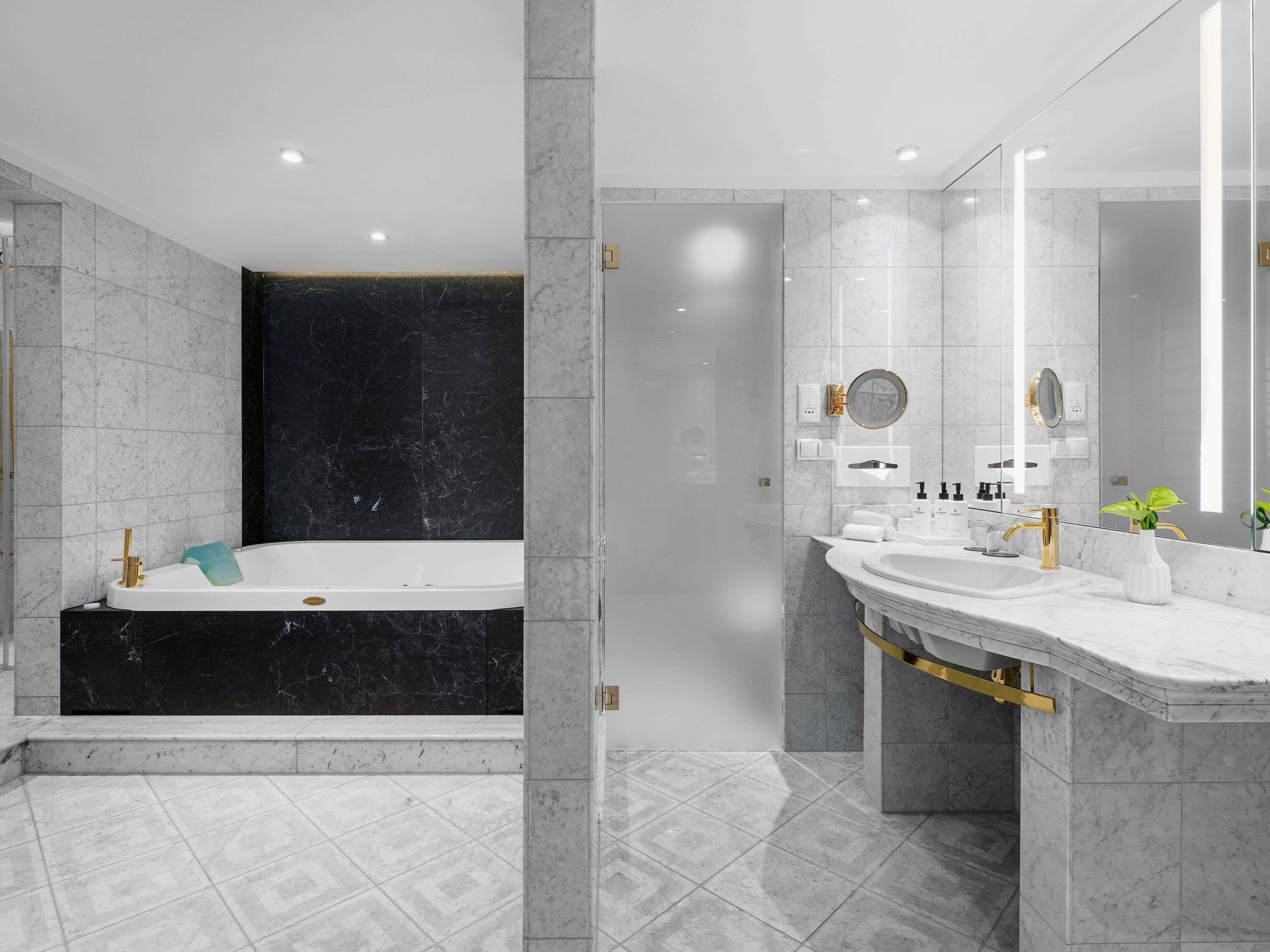 A modern bathroom with a bathtub, a large mirror, and a vanity with a sink.