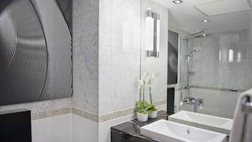 Een moderne badkamer met twee wastafels, een glazen douchecabine en decoratieve planten.