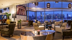 Un vestíbulo amplio con vistas panorámicas a la ciudad, asientos cómodos y una decoración moderna.