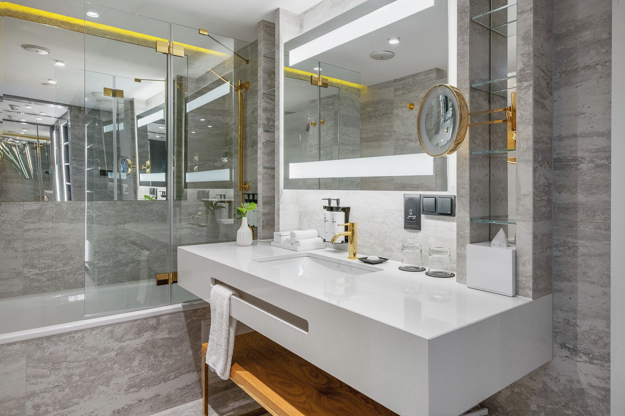 Un baño moderno con tocador blanco, un espejo grande y una cabina de ducha de vidrio.
