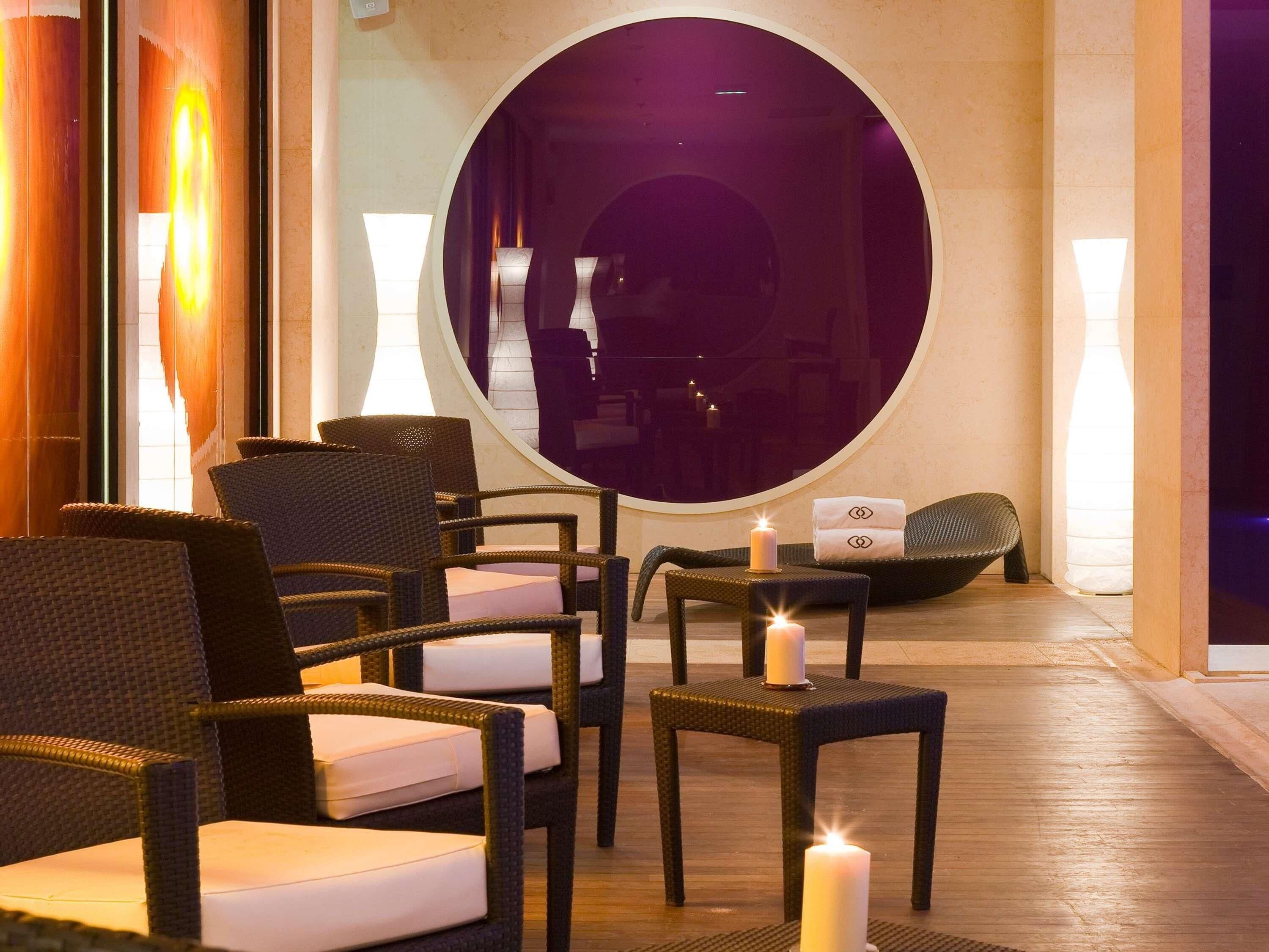 A seating area with wicker chairs and a round mirror.