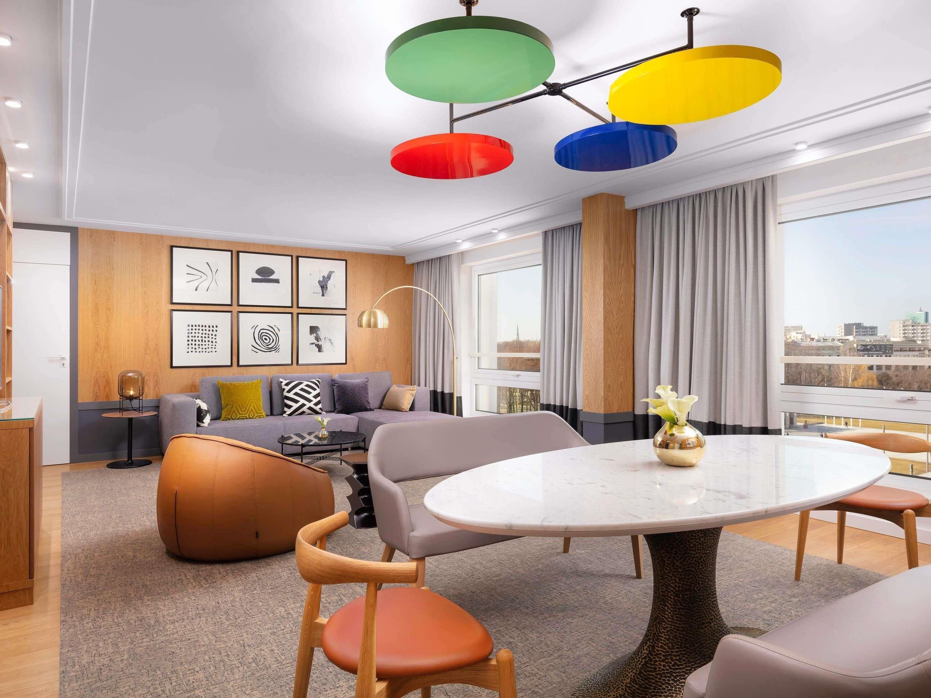 Une chambre d’hôtel moderne dotée d’un espace salon, d’une table à manger et offrant une vue sur la ville.