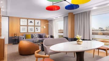 Una habitación de hotel moderna con sala de estar, una mesa de comedor y vistas a la ciudad.