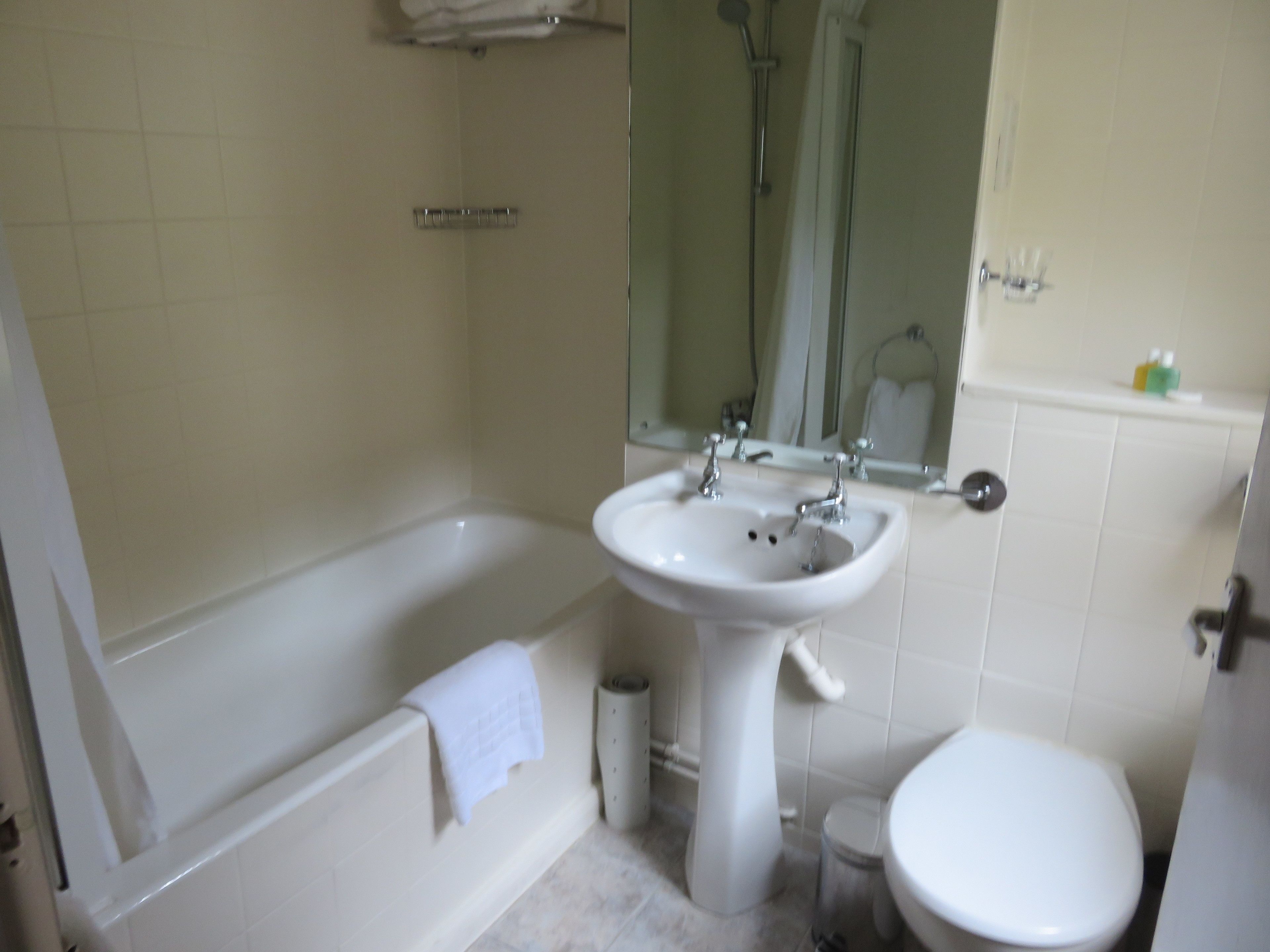 Un baño con bañera, lavamanos, inodoro y espejo.