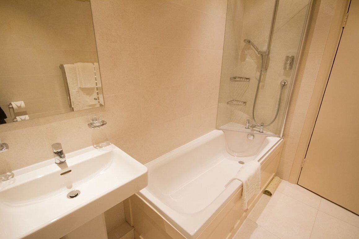 A bathroom with a white sink, a bathtub, and a glass-enclosed shower area.