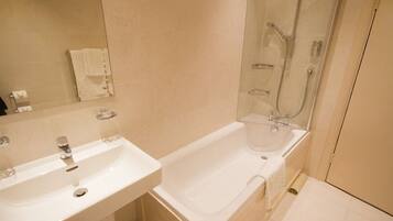 A bathroom with a white sink, a bathtub, and a glass-enclosed shower area.