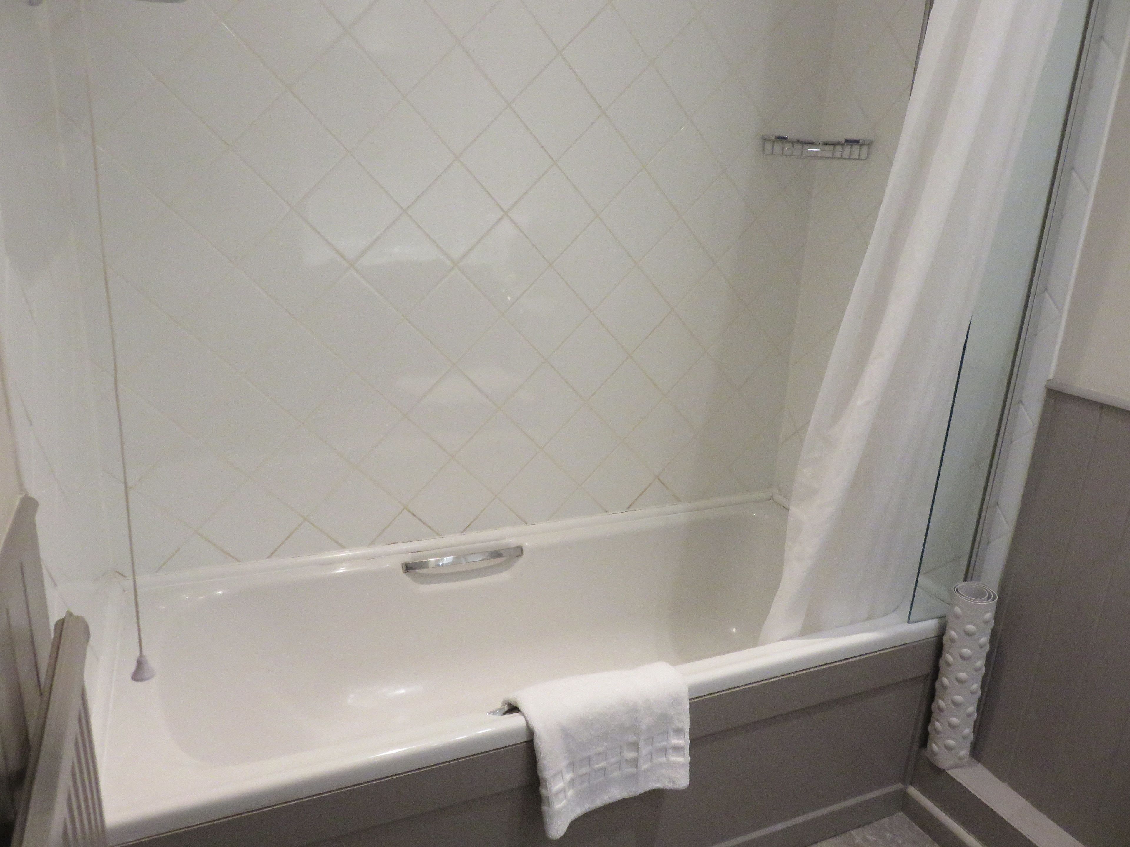 Une salle de bain moderne avec une baignoire blanche, une douche en verre et une serviette accrochée sur le côté.