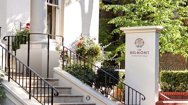 A building with a white facade, a staircase with black railings, and a sign reading "BELMONT DE MONTFORT STREET". - The Belmont Hotel (Leicester)