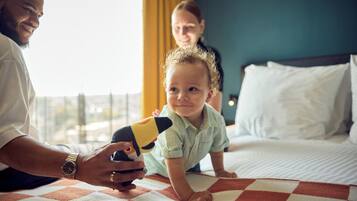 Een hotelkamer met een bed, een geruit plaid en een raam met gordijnen.