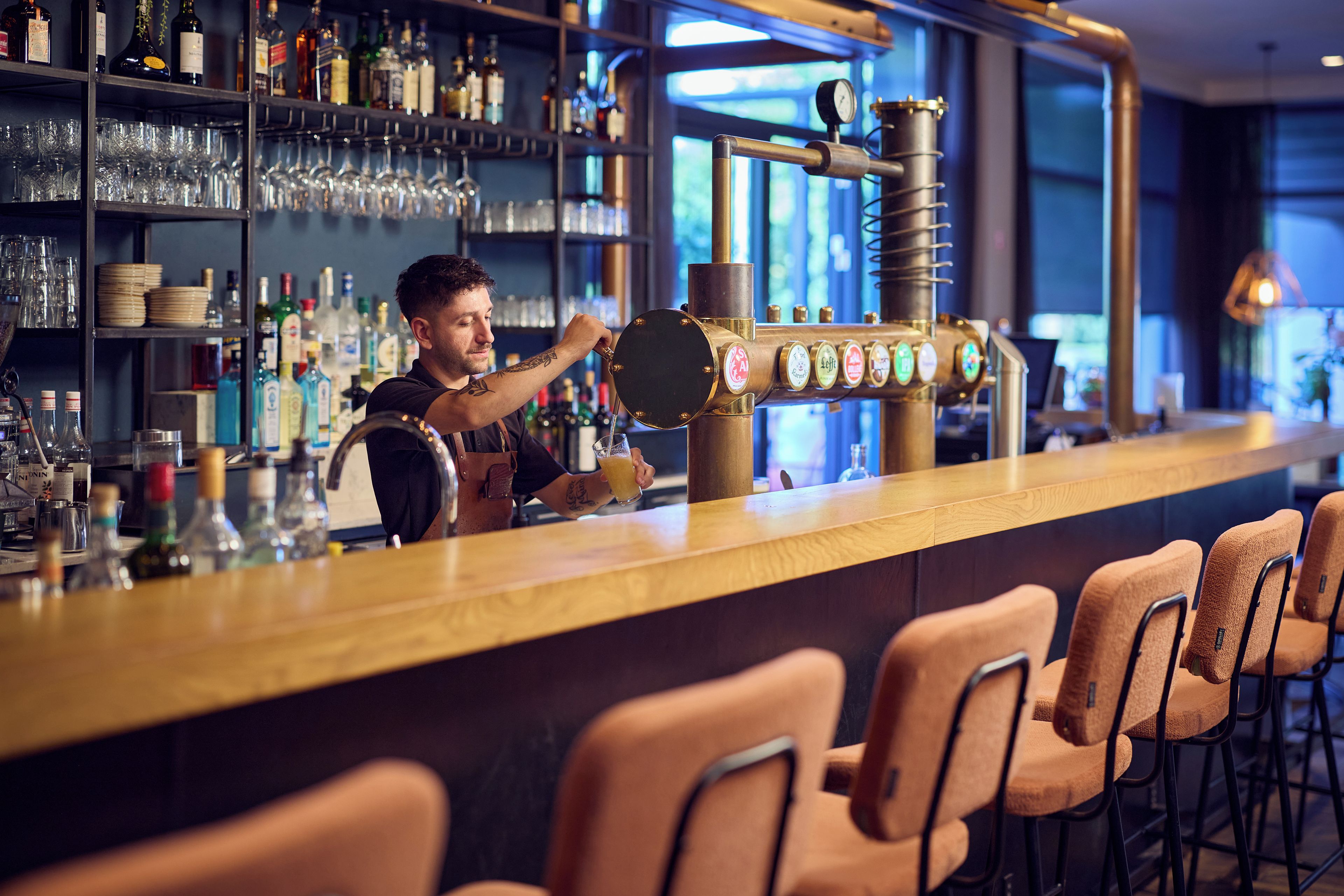 Un bar con sistema de grifos, vasos y botellas.