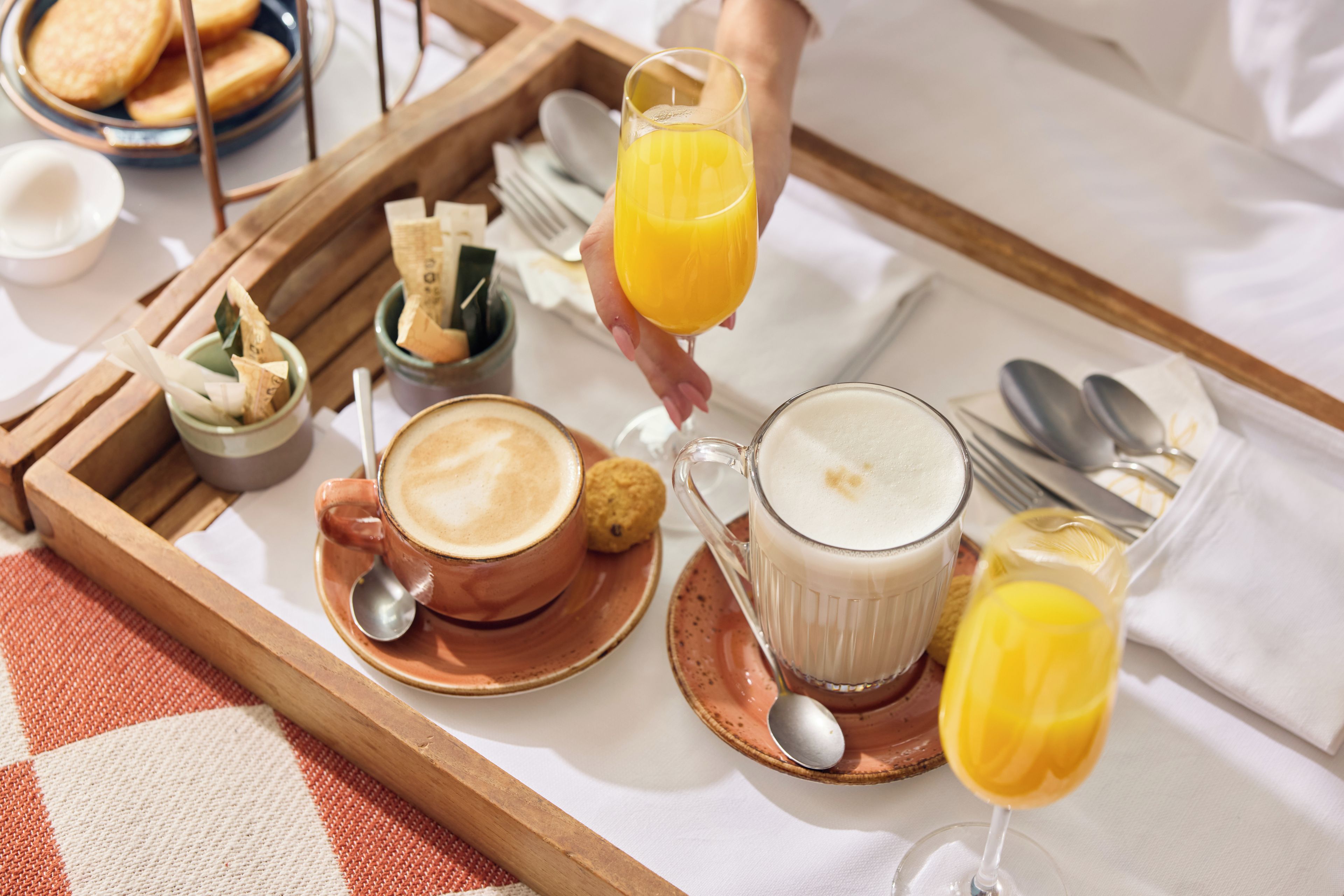 Una bandeja de desayuno con una taza de café, un vaso de jugo de naranja y una taza de leche.