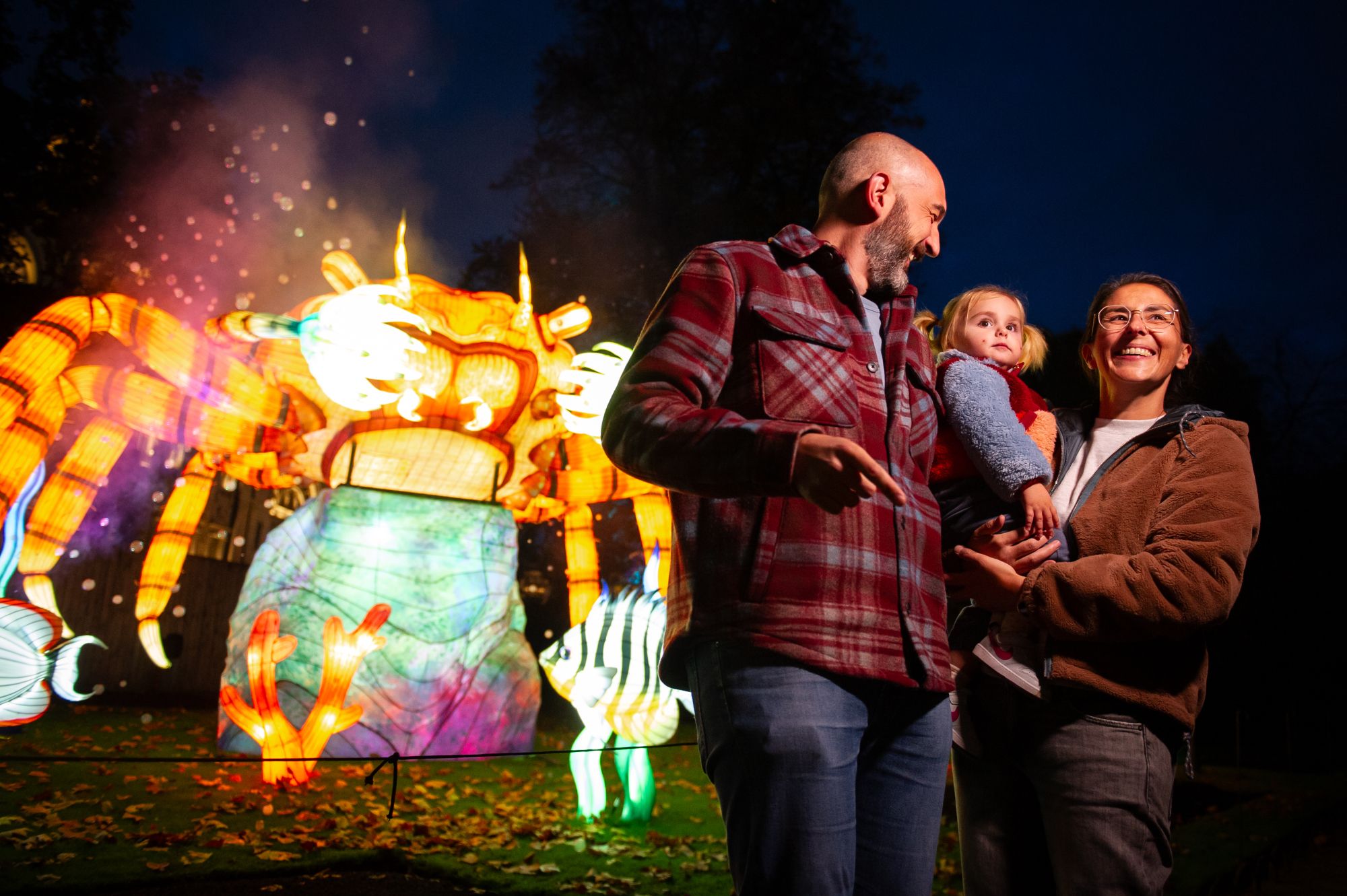 Une famille se tient devant une grande sculpture illuminée.