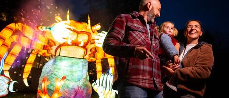 Una familia de pie frente a una gran escultura iluminada.