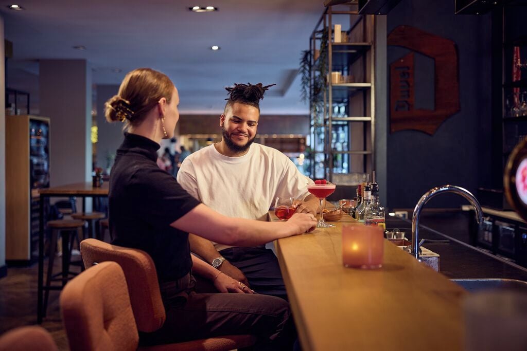 Un espace bar avec un comptoir, des tabourets et une étagère où sont rangées les bouteilles.