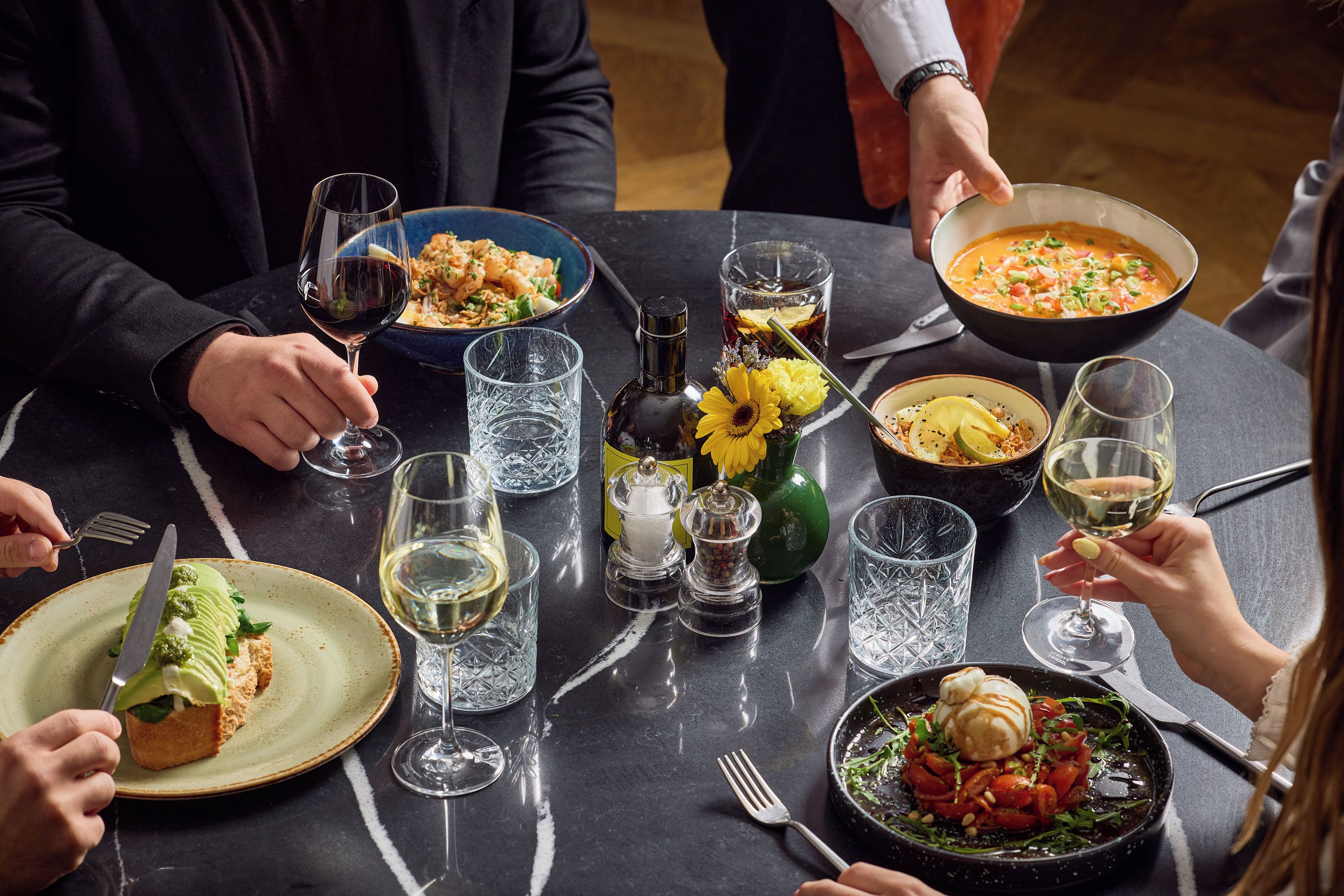 Una mesa de comedor con diferentes platos, copas de vino y una botella de agua.