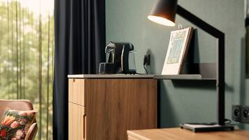 Een houten bureau met een koffiezetapparaat, een ingelijst menu en een lamp.