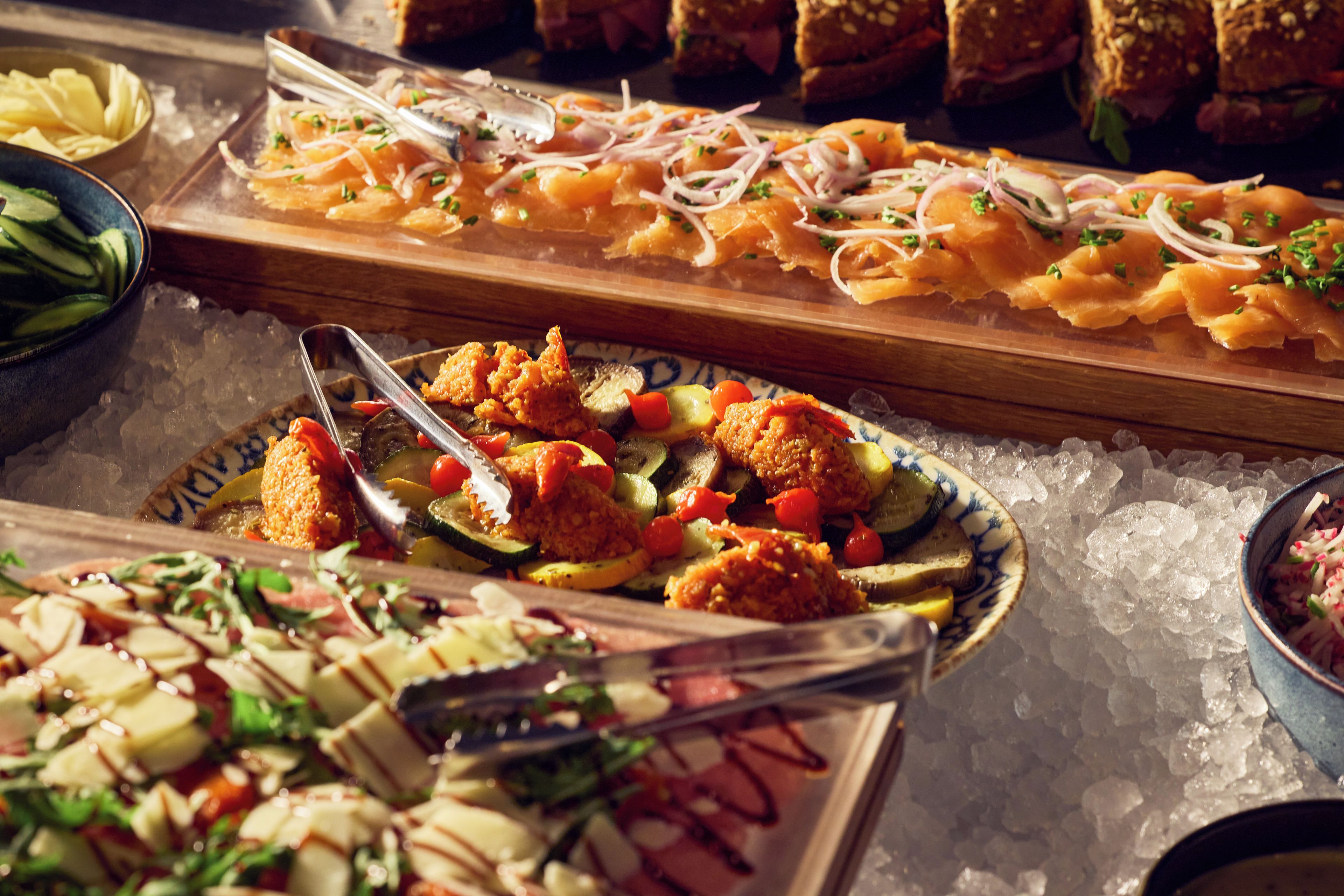 Un buffet proposant une variété de plats, notamment des fruits de mer, des légumes et du pain.