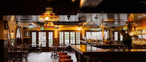 Un bar con muebles de madera, una barra y lámparas colgantes.