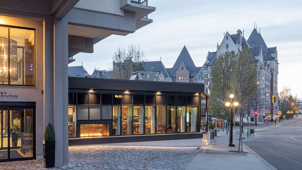 A DoubleTree hotel with a modern facade, large windows, and a visible fireplace. - DoubleTree by Hilton Hotel & Suites Victoria (Victoria)