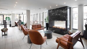 A modern lounge area with leather sofas, a central round table, and a fireplace. - DoubleTree by Hilton Hotel & Suites Victoria (Victoria)