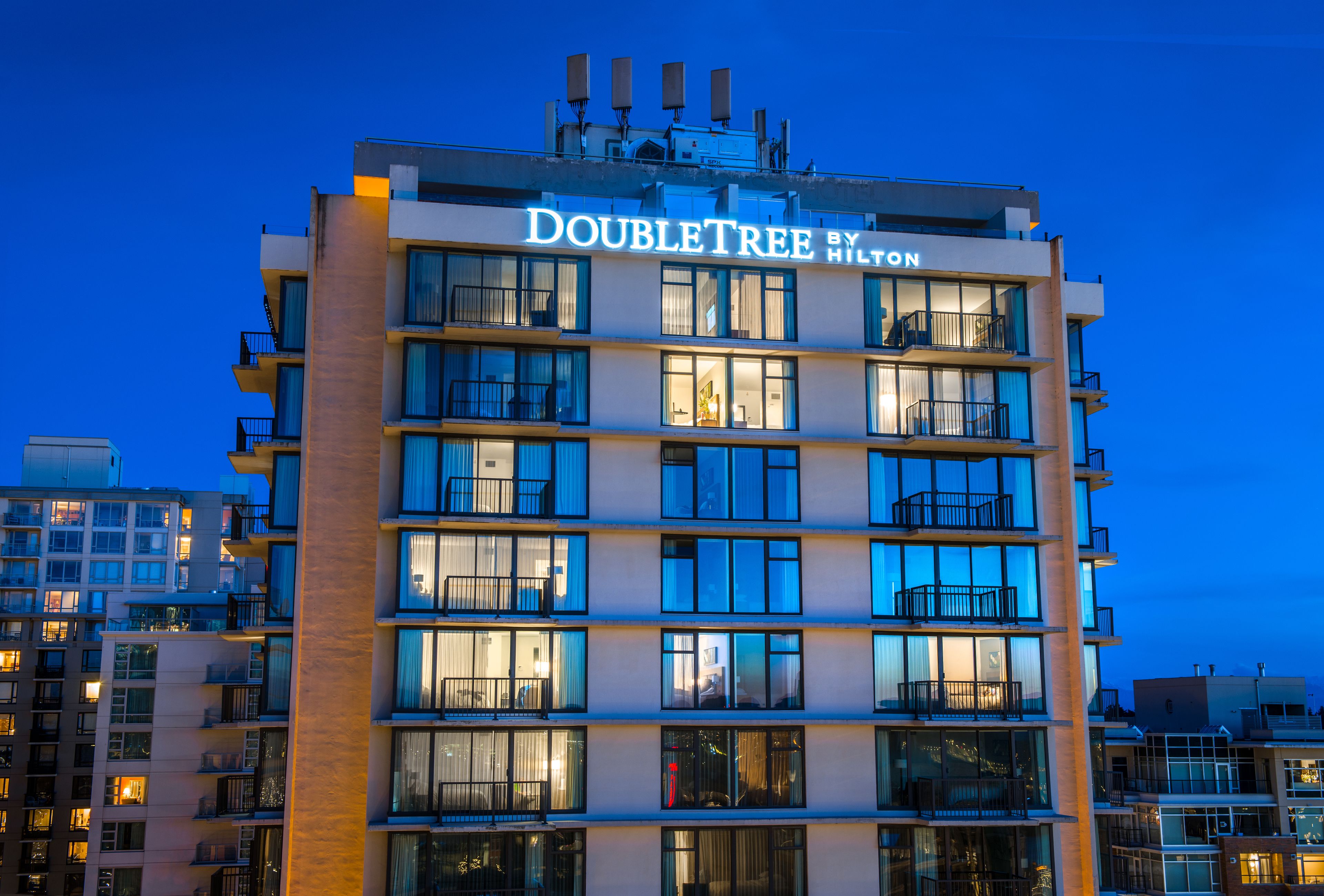 Un hotel a più piani chiamato "DOUBLETREE BY HILTON" con finestre e balconi illuminati.