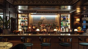 A bar area with a high bar counter, multiple stools, and a variety of bottles and glasses. - DoubleTree by Hilton Hotel & Suites Victoria (Victoria)