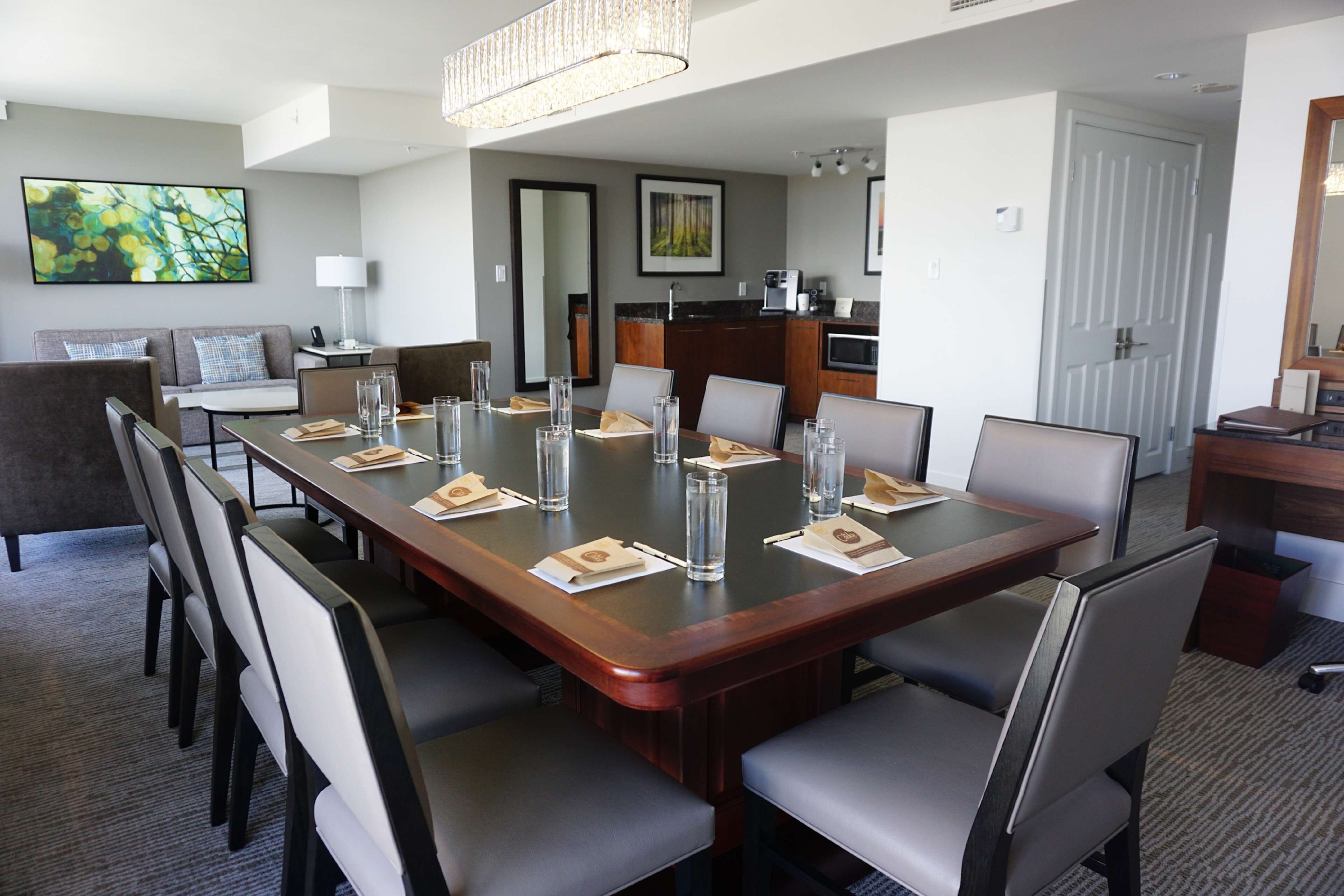 Une salle de conférence avec une longue table, des chaises et un coin cuisine à l’arrière-plan.