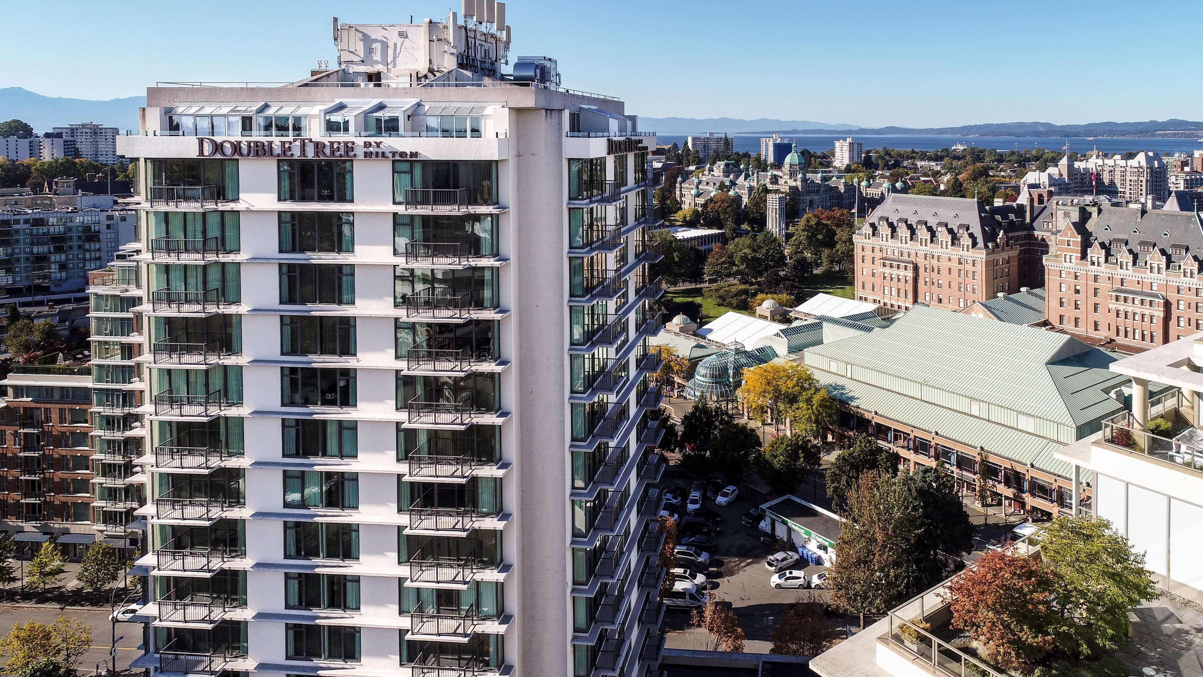 Un moderno hotel de gran altura con varios balcones, un letrero llamativo que dice "DOUBLE TREE BY HILTON" y vistas de la ciudad circundante, incluyendo edificios históricos y una zona ribereña.