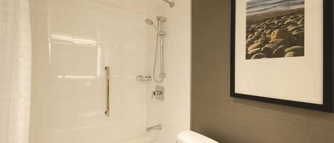A bathroom with a bathtub, toilet, and a framed picture on the wall.