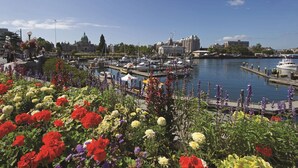 A marina with boats docked, a large building with a dome in the background, and a variety of flowers in the foreground. - DoubleTree by Hilton Hotel & Suites Victoria (Victoria)