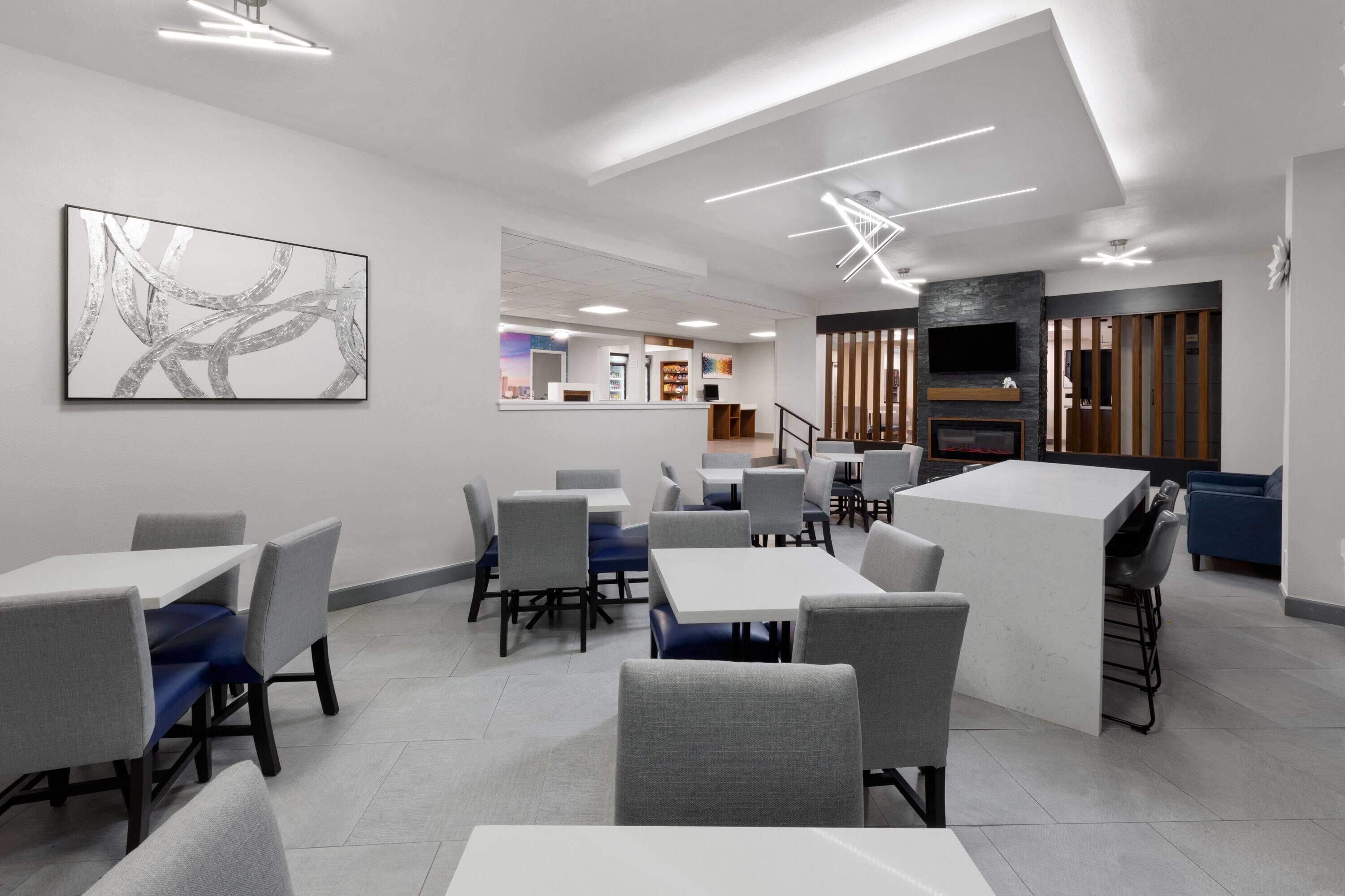 A modern restaurant with a mix of seating options, including tables and booths, and a large abstract painting on the wall.