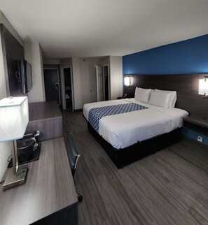 Een hotelkamer met een groot bed, een bureau met lamp, een televisie en een kledingkast.