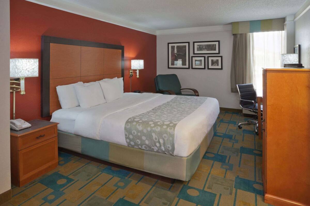 Hotelkamer met een groot bed, een bureau met telefoon, een stoel, een bureaulamp en wanddecoraties.