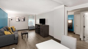 A modern living room with a gray sofa, a white coffee table, and a TV on a wooden cabinet.