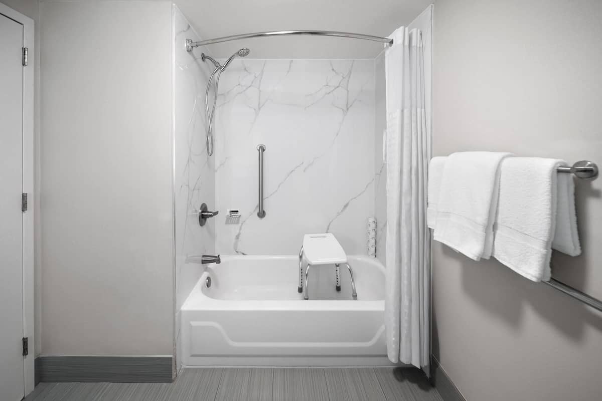 Een moderne badkamer met een inloopdouche, een bad en een handdoekhouder.