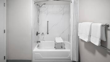 A modern bathroom with a walk-in shower, a bathtub, and a towel rack.