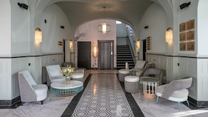 A lobby with a geometric patterned carpet, seating areas, and a staircase.