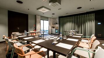 A conference room with a long table, chairs, water bottles, and a view of the outdoors.