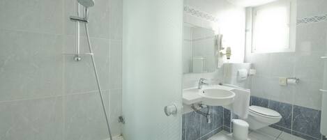 A modern bathroom with a shower, sink, and toilet.