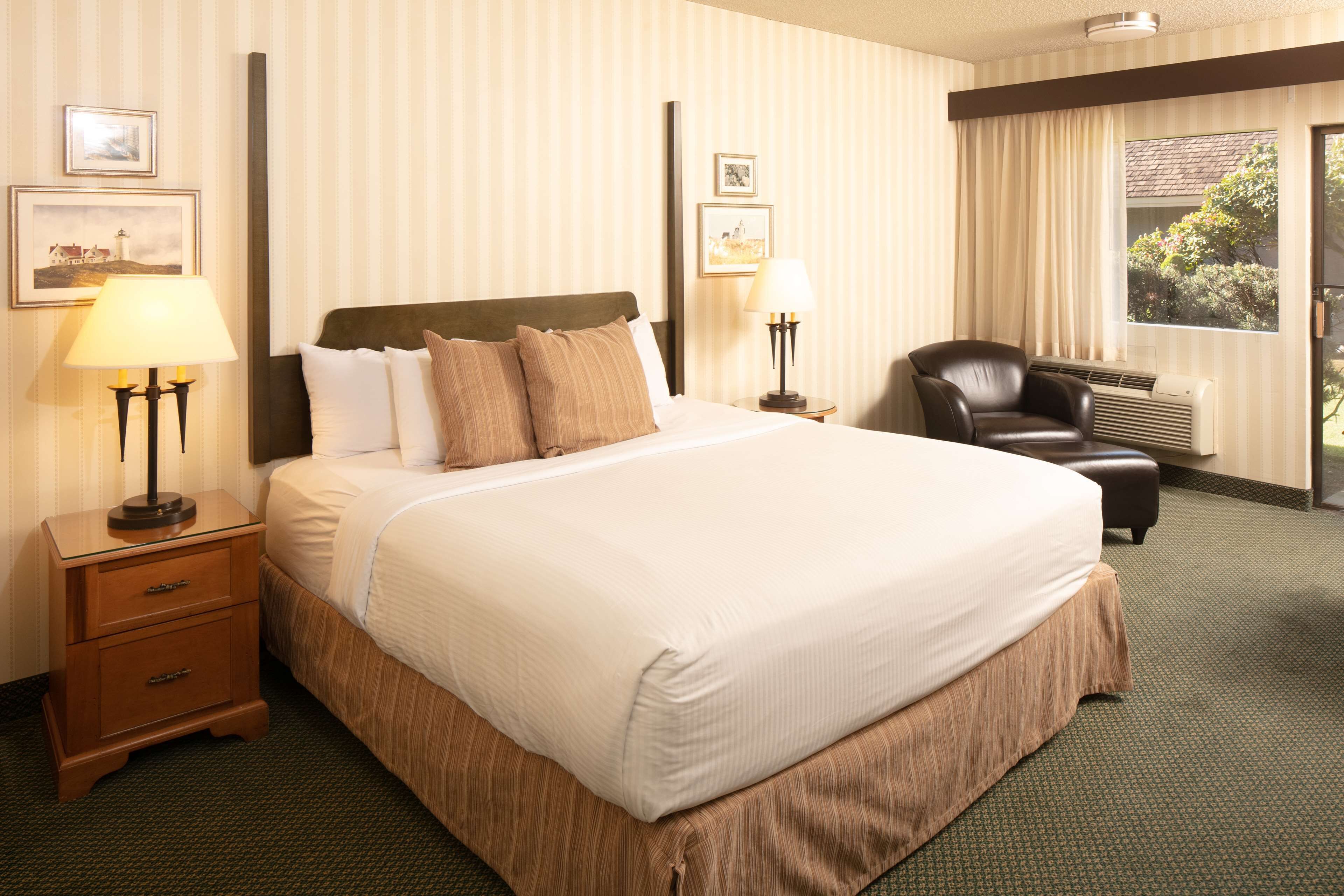 A hotel room with a large bed, two bedside tables with lamps, a chair, and a window with curtains.