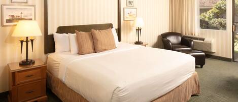 A hotel room with a large bed, two bedside tables with lamps, a chair, and a window with curtains.
